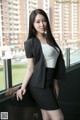 A woman in a business suit leaning against a window.