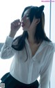 A woman in a white shirt and black skirt smoking a cigarette.