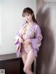 A woman in a purple kimono posing for a picture.