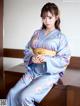 A woman in a blue kimono sitting on a wooden table.