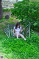 A woman sitting on a bench in the grass.