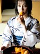 A woman in a kimono eating a piece of fruit.