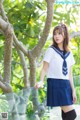 A woman in a school uniform holding a flower.