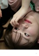 A young girl laying on the floor with her hands on her face.