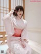 A woman in a pink kimono sitting on a window sill.