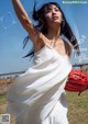 A woman in a white dress holding a baseball glove.