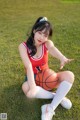 A woman sitting on the grass holding a basketball.