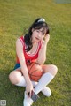 A woman sitting on the grass holding a basketball.