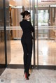 A woman in a black suit standing in front of a glass door.