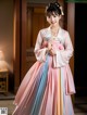 A woman in a pink and blue hanbok is posing for a picture.