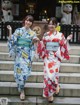 Two women in kimonos are walking down some steps.