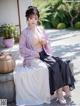 A woman in a purple kimono sitting on a bench.