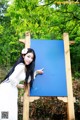 A woman in a white dress standing next to a blue sign.